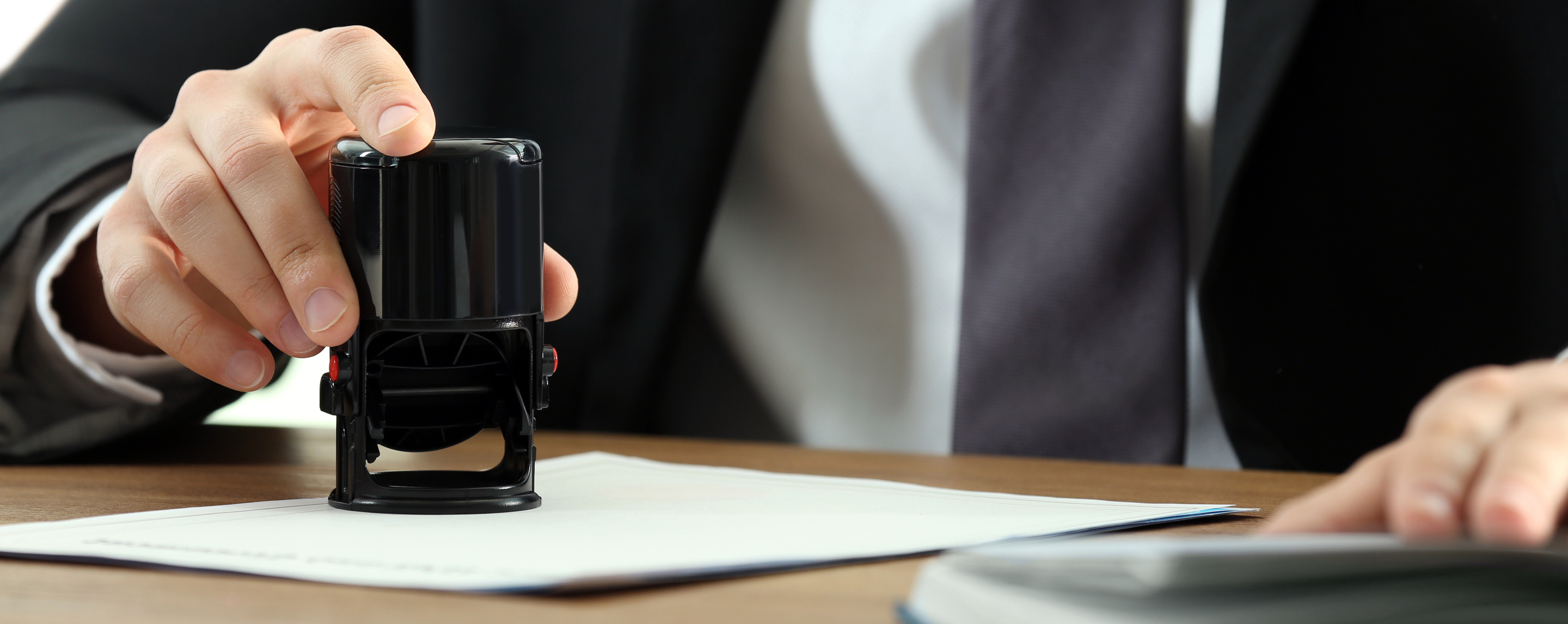 Male Notary Stamping Document at Table, Closeup